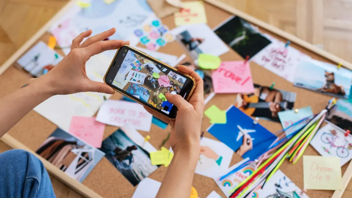 Seseorang menggunakan smartphone untuk mendokumentasikan moodboard kreatif, langkah awal penting dalam merancang identitas visual yang konsisten untuk Brand Awareness Strategy.