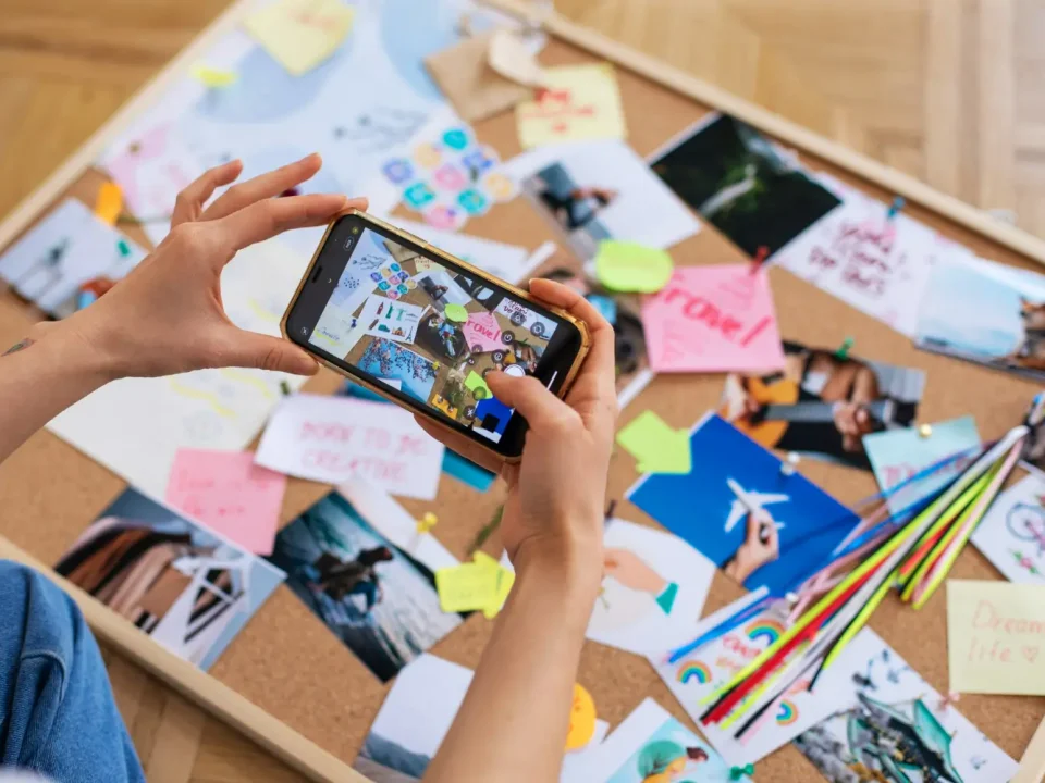 Seseorang menggunakan smartphone untuk mendokumentasikan moodboard kreatif, langkah awal penting dalam merancang identitas visual yang konsisten untuk Brand Awareness Strategy.