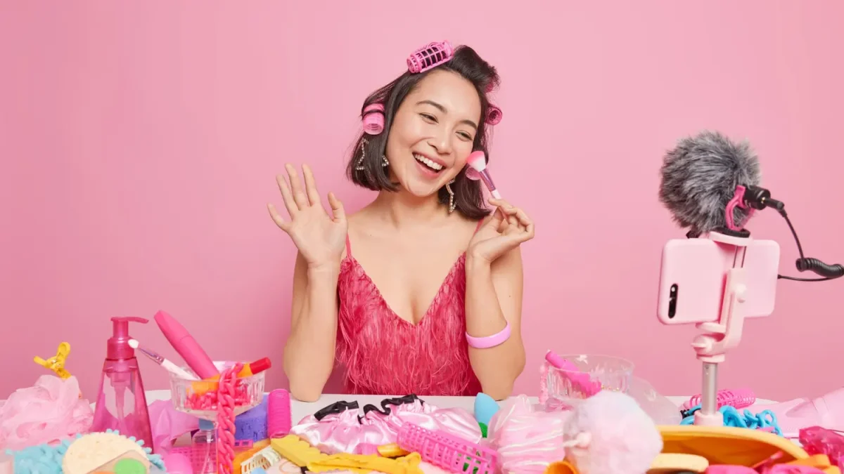 Seorang beauty influencer wanita sedang membuat konten video review produk di depan smartphone, sebuah contoh nyata dari penerapan strategi influencer marketing.